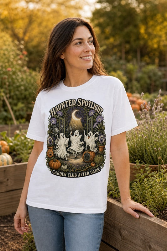 Woman wearing a white Haunted Spotlight Garden Club Halloween graphic T-shirt outdoors
