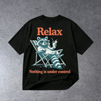 RELAX NOTHING IS UNDER CONTROL FUNNY RACCOON GRAPHIC T-SHIRT on light gray concrete